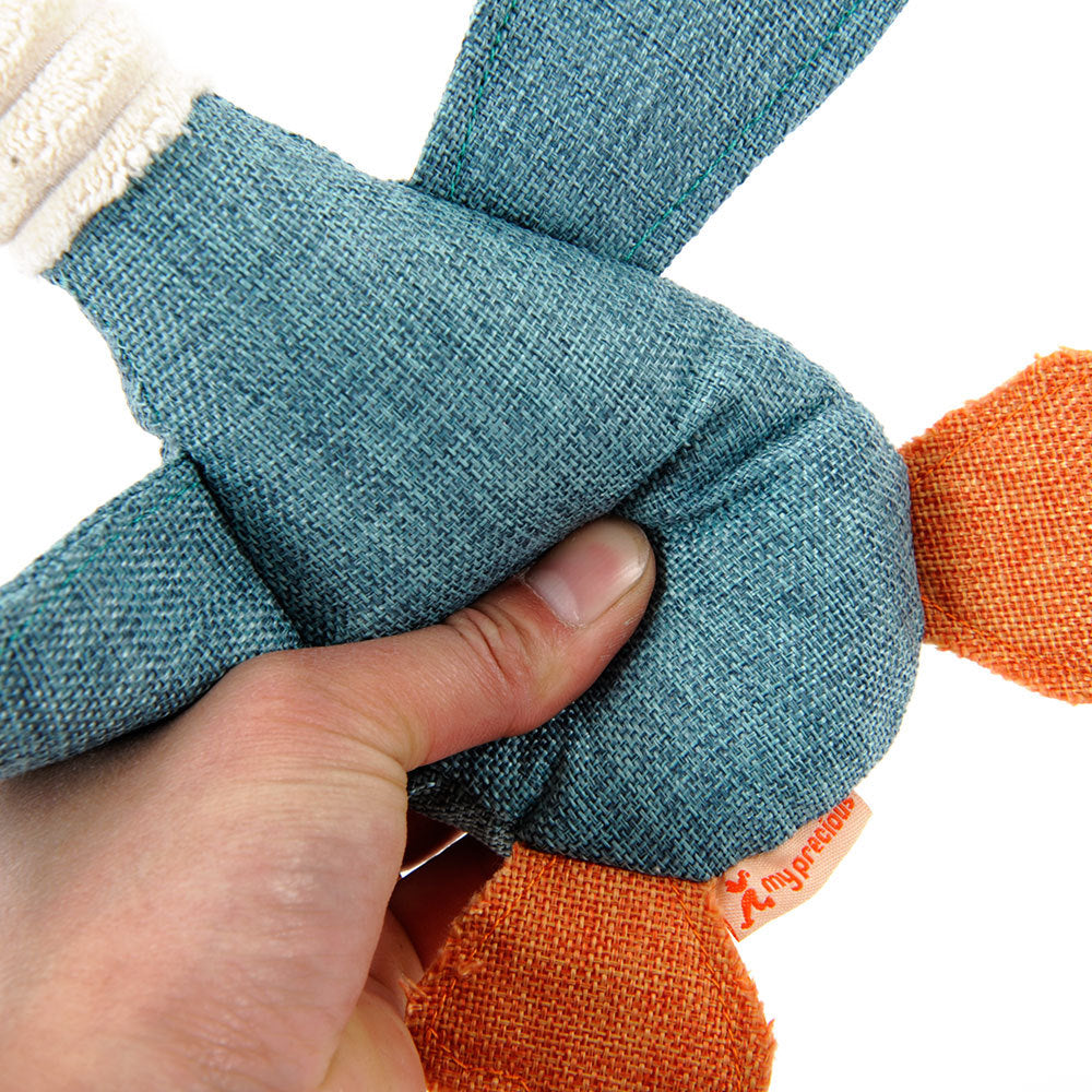 A hand holding an interactive plush squeaky dog toy featuring colorful fabric and soft textures.