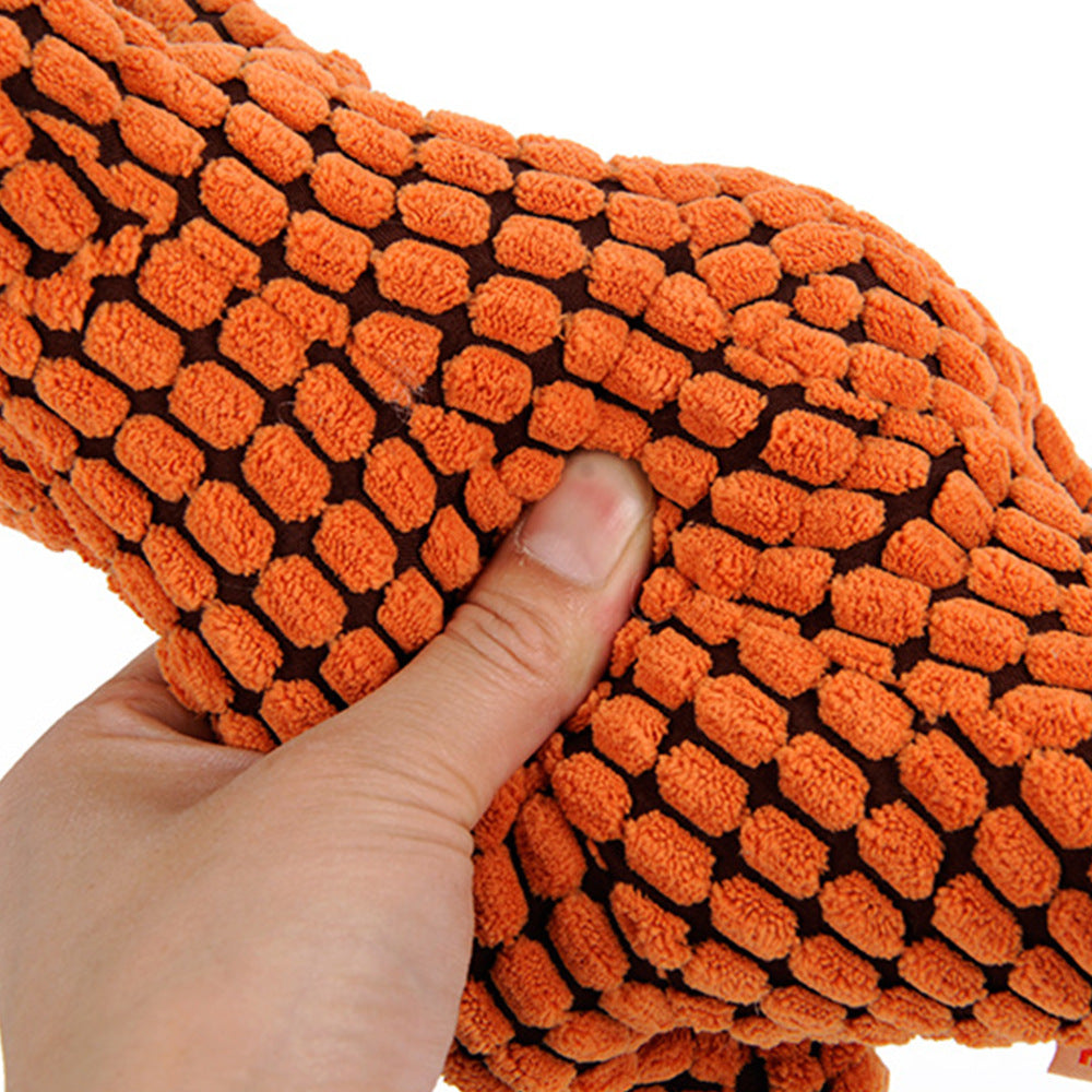 Close-up of a person squeezing a soft dinosaur squeaky dog toy in orange color.