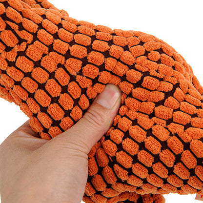 Close-up of a person squeezing a soft dinosaur squeaky dog toy in orange color.