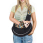 Woman using a pet crossbody carrier bag to comfortably hold a small dog during outdoor activities.