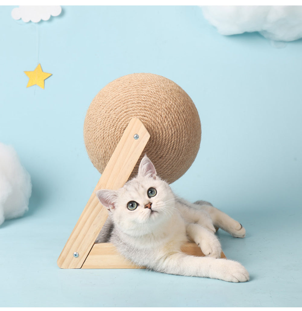 A playful cat lying next to a sisal vertical cat toy with a round textured ball on a wooden base.