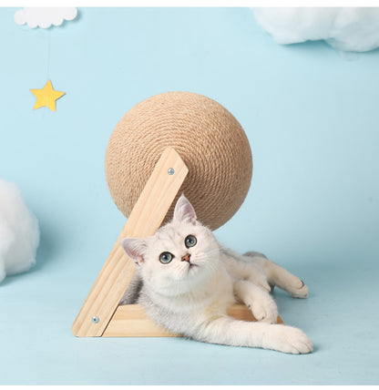 A playful cat lying next to a sisal vertical cat toy with a round textured ball on a wooden base.