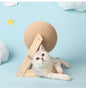 A playful cat lying next to a sisal vertical cat toy with a round textured ball on a wooden base.